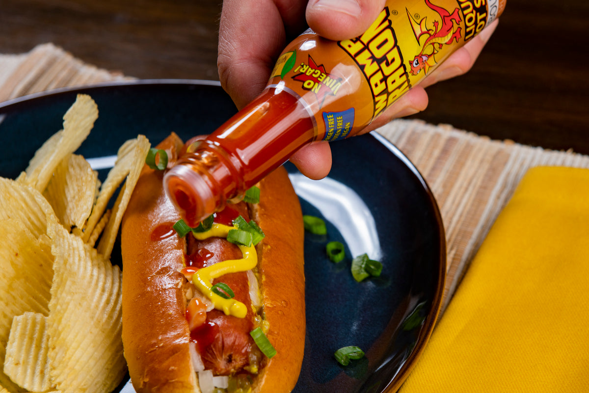 Bourbon Dragon Hot Sauce pouring out onto a hot dog
