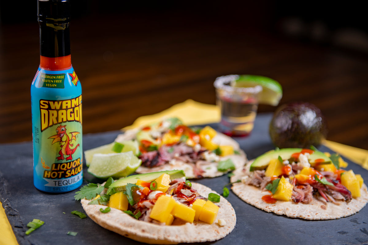 Bottle of Swamp Dragon Tequila Hot Sauce with pulled pork and mango tacos