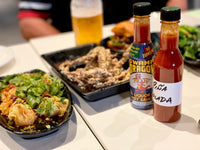 Bottle of Ouzo Hot Sauce and a hand labeled Piña Colada Hot Sauce next to Asian foods